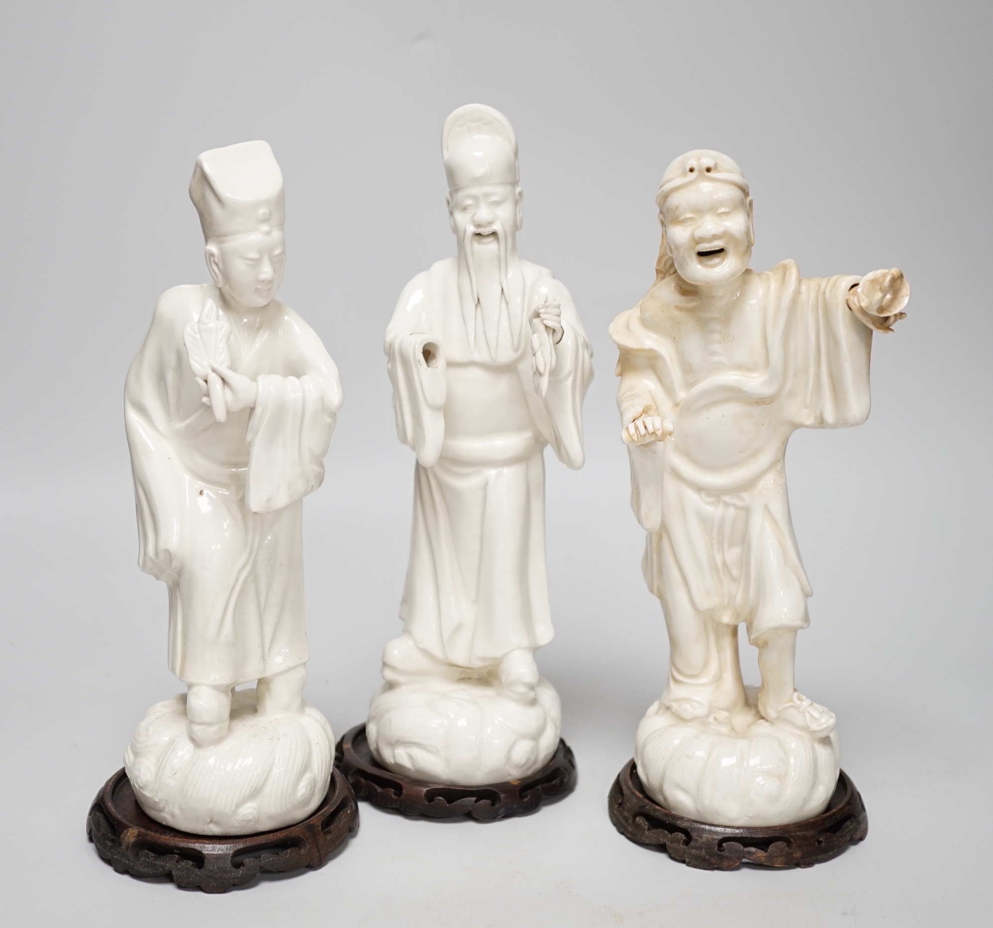 Seven Chinese blanc de Chine figures of immortals, each raised on carved hardwood bases, the largest 24cm high